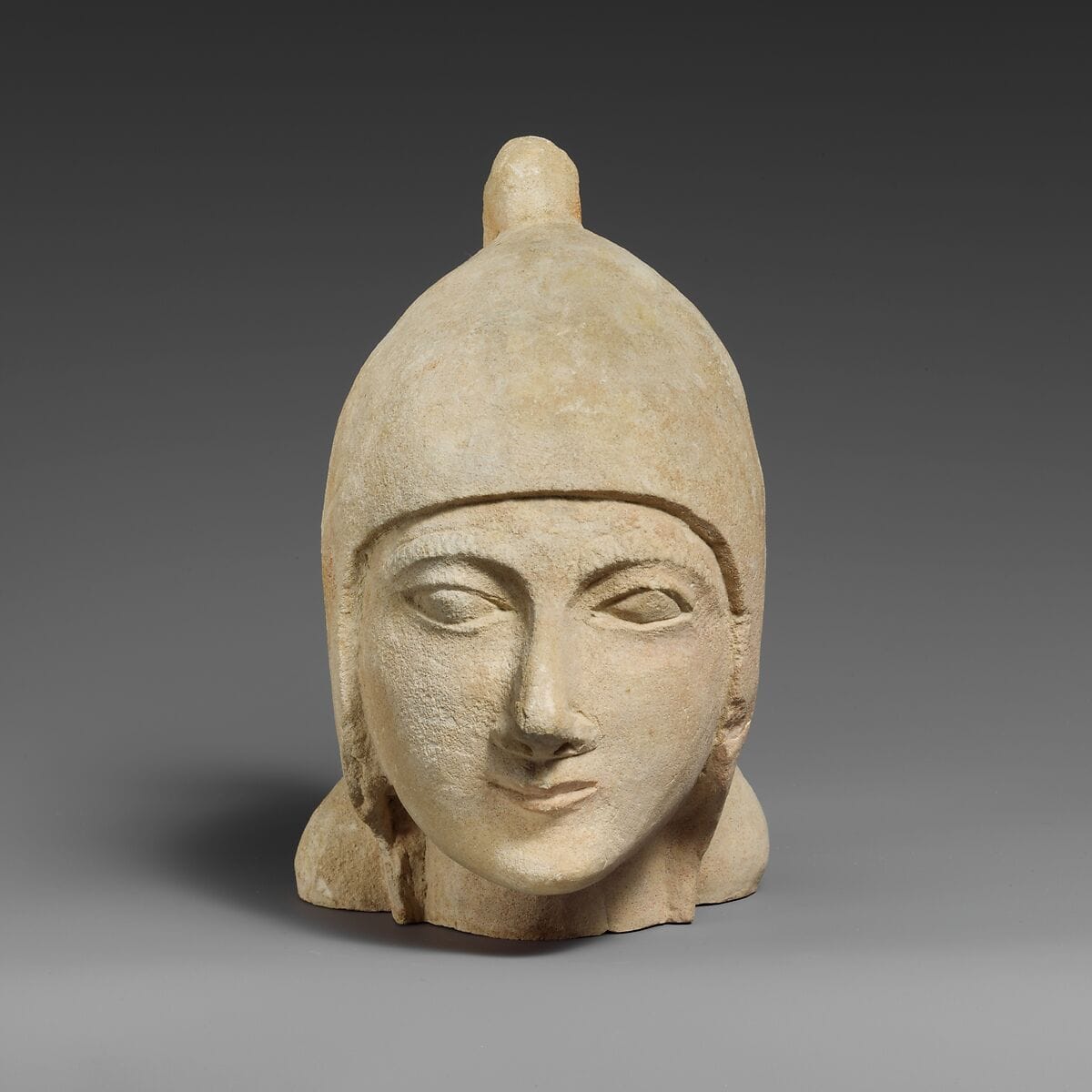 Limestone head of a beardless male wearing a conical helmet - image 1