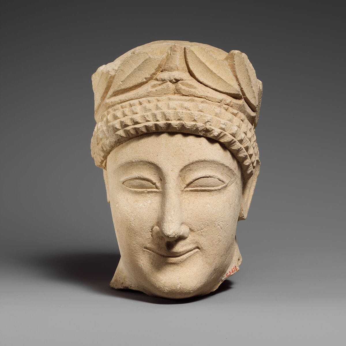 Limestone head of a beardless male votary with a wreath of leaves - image 1
