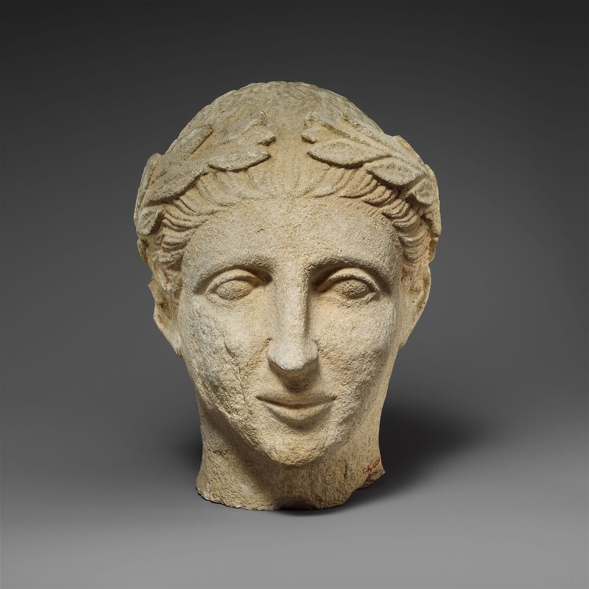 Limestone head of a beardless male votary with a wreath of leaves - image 1