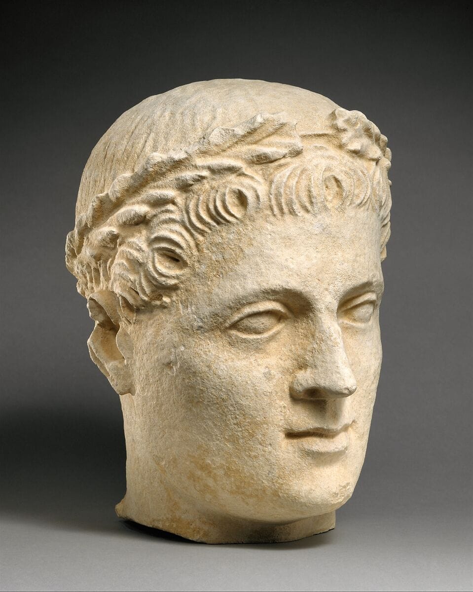 Limestone head of beardless male votary with wreath of leaves - image 1