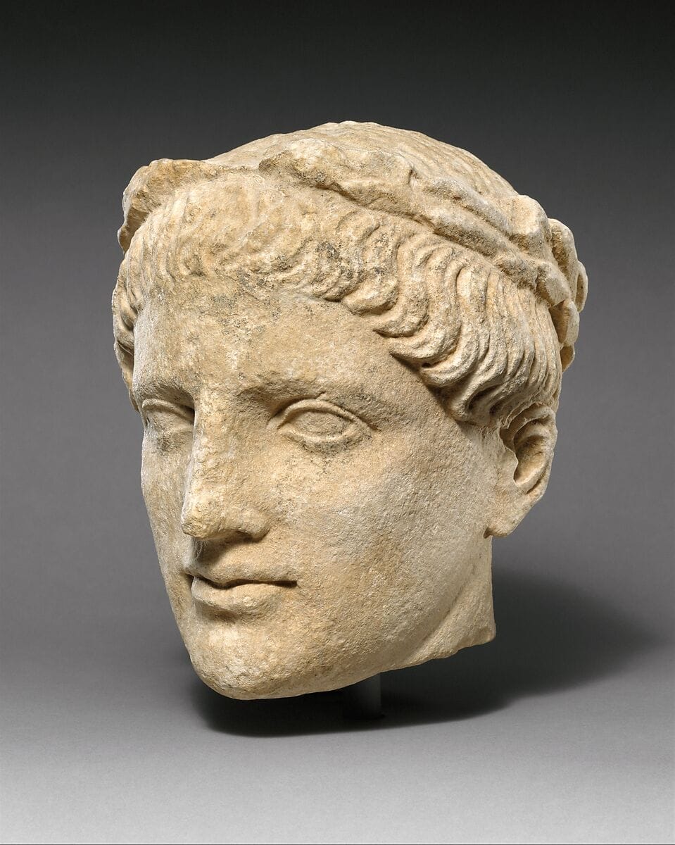 Limestone head of beardless male votary with wreath of leaves - image 1